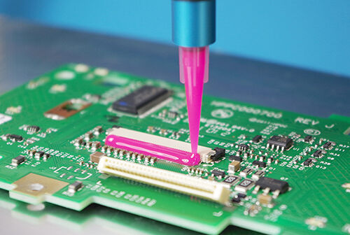 Vitralit UD 2018, a pink electronic adhesive from Panacol as corner bonding is dosed onto a PCB